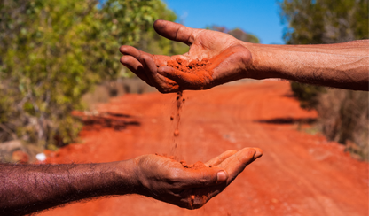 Red earth falling ffom one hand to another